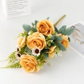 Detailed view of artificial orange rose bouquet with white daisies and green leaves on white surface - Orange