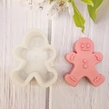 Silicone gingerbread man mold and pink handmade candle on white wooden background - Snowman
