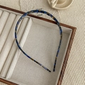 Dettaglio di un cerchietto in acetato tartarugato blu e marrone su un vassoio di legno - Blu Scuro PVC