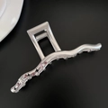 Macro view of matte silver hair claw clip with purple rhinestones and star cutouts - Bar Style