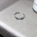 Detail eines silbernen offenen Rings mit blau-weißen Zirkonia-Kleeblatt-Motiven. - Vierblättriges Kleeblatt Gliederstil (24#) / Blaue Blume