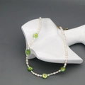 Detail van zoetwaterparelketting met groene madeliefjes op een witte etalagepopnek - Groen