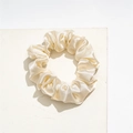 Detailed view of luxury champagne satin scrunchie on a white marble display stone - Small Satin Beige