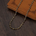 Goldene Halskette mit schwarz-weißen Evil Eye Perlen auf Vintage-Holzkiste - Schwarz