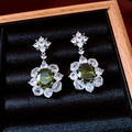 Detailed view of vintage flower earrings with green gemstone and zirconia on black velvet - Silver Needle - Green - Transparent