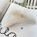 Primer plano de una pinza de pelo grande color crema sobre una revista elegante - Blanco Gelatina