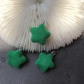 Close-up of green flocked star charms with silver metal rings on a textured background - Green