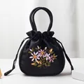 Ethnic style black satin drawstring handbag featuring floral embroidery and round handles - Black