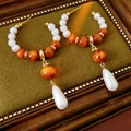 Detalle de pendientes de gota con perlas y resina naranja sobre un marco elegante - Aguja de Plata-Blanco-Café