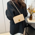 Quilted beige shoulder bag with gold twist lock and chain strap on a female model - Khaki