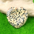 Polished Dalmatian Jasper heart worry stone placed on a green artificial lawn - Dalmatian Jasper