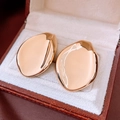 Detailed macro view of large polished gold-tone teardrop earrings in a jewelry box - Gold / Gold