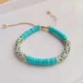 Detail of handmade beaded bracelet with teal heishi clay beads and golden spacers - Cyan Striped Polymer Clay Style (RTS220002G)