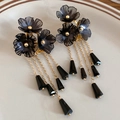 Primer plano de aretes de flores de cristal negro con elegantes borlas doradas y colgantes - Negro