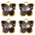 Macro detail of four smoke grey crystal butterfly charms with golden metal frames - Smoke