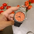 Macro detail of the silver stainless steel band and vibrant orange dial with date display - Silver Case Orange Dial