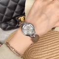 Women's quartz watch with spinning snowflake dial and taupe leather strap worn on wrist - Silver Gray