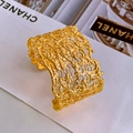 Macro detail of wide gold-plated cuff featuring organic lava cutout texture and shiny finish - Cutout Lava Style / Gold