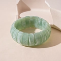 Detail view of wide elastic acrylic bracelet with green marble texture on stone props - Green
