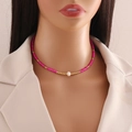 Detail of beaded choker necklace featuring pink beads, gold accents and a center pearl - Rose Red
