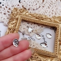 Close-up of a sparkling skull-shaped titanium crystal stud earring held by hand - White