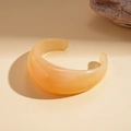Detail of wide open resin bangle with amber yellow marble pattern and polished finish - Beige