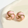 Detail of pink enamel and gold knot vortex earrings on a warm ceramic background - Pink