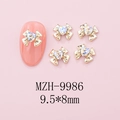 Macro view of 9.5x8mm bow-knot nail art charms with heart crystal and golden alloy base - Gold Bow + White Moonstone Heart (9986)