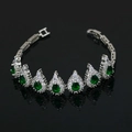 Detalle de pulsera plateada con gemas verdes de pera y cristales sobre fondo negro - Pulsera de Circonita Verde