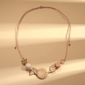 Detalle de collar bohemio con disco de ratán trenzado y cuentas de madera geométricas - Beige