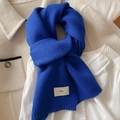 Royal blue knitted scarf with decorative emo tag on beige wool coat background - Klein Blue