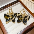 Detailaufnahme der Leopardenmuster-Schmetterlingsohrringe auf einer hochwertigen Schmuckschatulle - Leoparden Schmetterling Stil / Goldschwarz