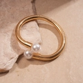 Close-up of golden spring-style collar necklace with elegant white pearls on stone - Bracelet-Gold