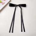 Détail d'un nœud en ruban satin noir avec de longs pans sur un fond blanc épuré - Noir