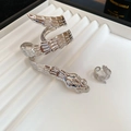 Macro shot of silver snake bracelets with intricate scale textures on a white tiered stand - Silver