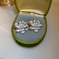 Detail view of pearl flower stud earrings with gold edges on green velvet display - Silver Earring Post-White