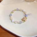 Detail eines Perlenarmbands mit Opal-Perlen und einem rosa Elefanten-Anhänger auf Teller - Opalblatt Elefanten Stil