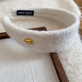 Detail of white flocked headband featuring a gold Korea tag and handmade label - White