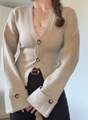 Dettaglio del cardigan in maglia color avena con scollo a V, bottoni tartarugati e polsini ampi - S / Albicocca
