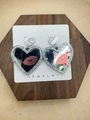 Detail of silver glitter heart earrings with lip motifs on a wooden display base - Heart Mirror Lips