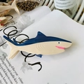 Blau-beige Hai-Haarklammer aus Acetat auf einem Buch im minimalistischen Meeres-Design - Blauer Hai