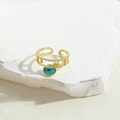 Detailaufnahme eines vergoldeten Evil Eye Rings auf einer weißen Marmorplatte - Grüne Emaille (JZ0999-6)