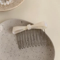Elegant white acetate bow hair comb with ten metal teeth on a ceramic tray - Pearl White