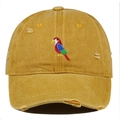 Close-up of parrot embroidery and distressed details on yellow washed cotton cap - Orange