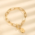Macro-opname van goudkleurige schakelarmband met rechthoekige sterhanger en OT-sluiting - Gouden Armband