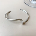 Detail of minimalist silver-colored twisted wavy open cuff bracelet with glossy finish - Silver