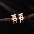 Macro shot of rose gold puppy earrings with heart cutout on a natural wooden branch - Rose Gold