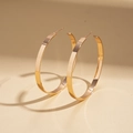 Detailed close-up of large flat gold hoop earrings with a mirror polished finish - Stud Earrings / Gold