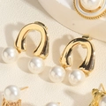 Macro view of gold U-shaped earrings with white pearls and premium metal texture - Rainbow Pearl Earrings (ES2320-4)