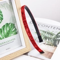 Detail of a thin red glitter headband resting on a wooden frame with a clean aesthetic - Red